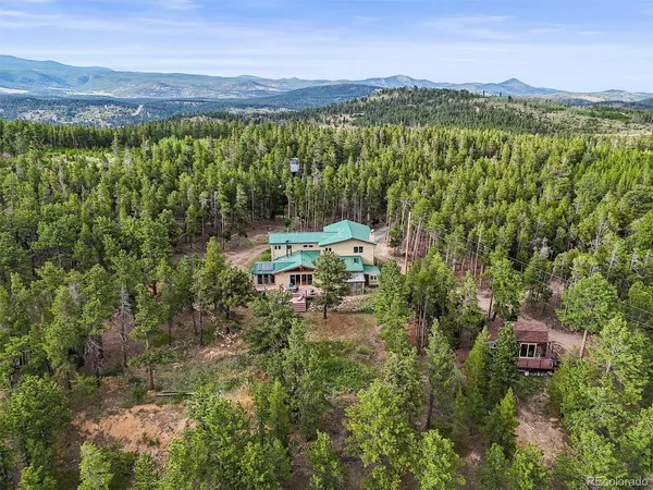 an aerial view of residential house with outdoor space and trees all around