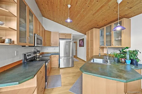 a kitchen with stainless steel appliances granite countertop a sink a stove and a wooden cabinets