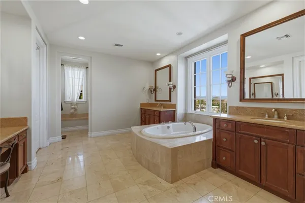 a spacious bathroom with a tub sink and mirror