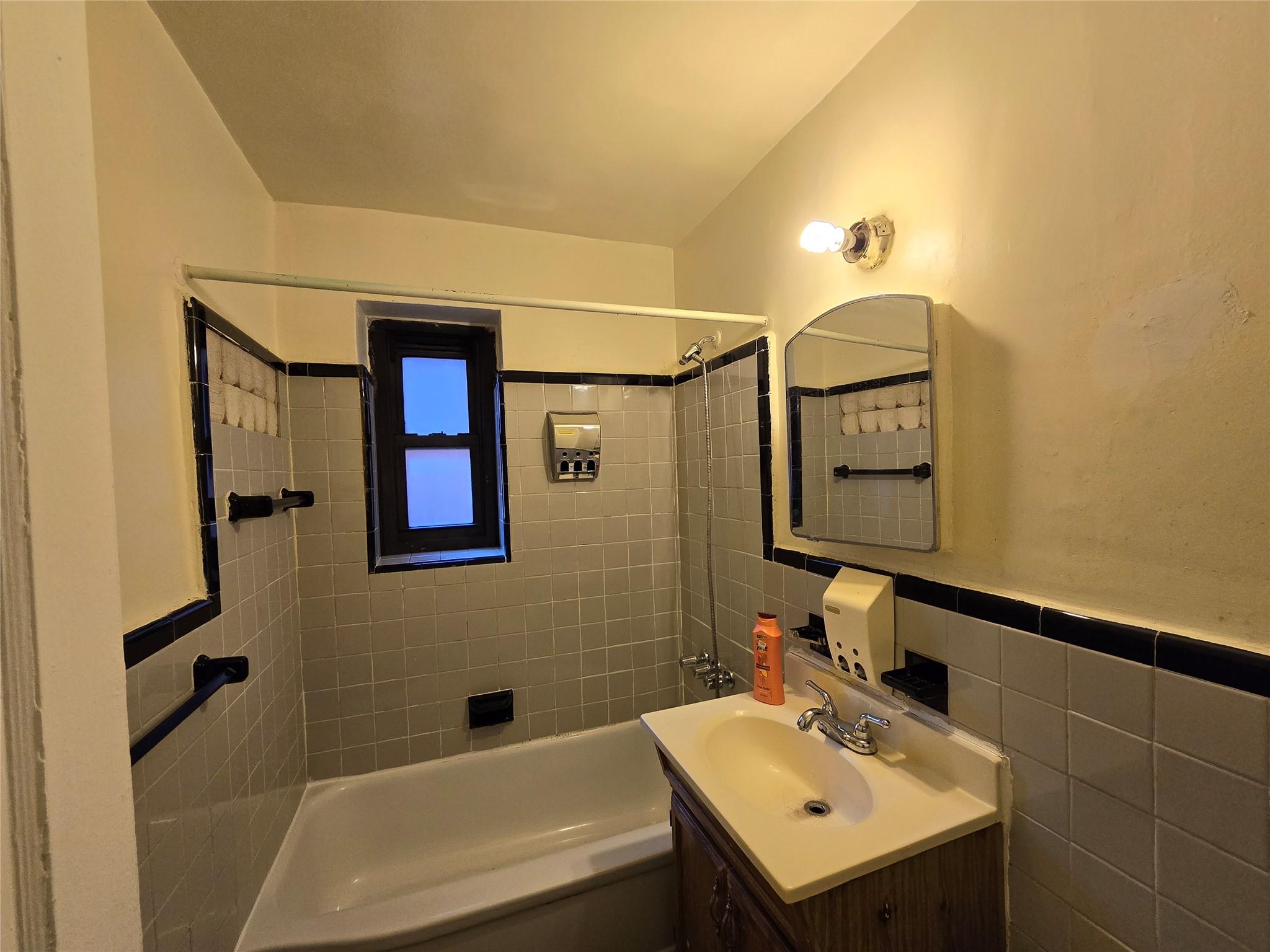 Bathroom with tile walls, vanity, and tiled shower / bath