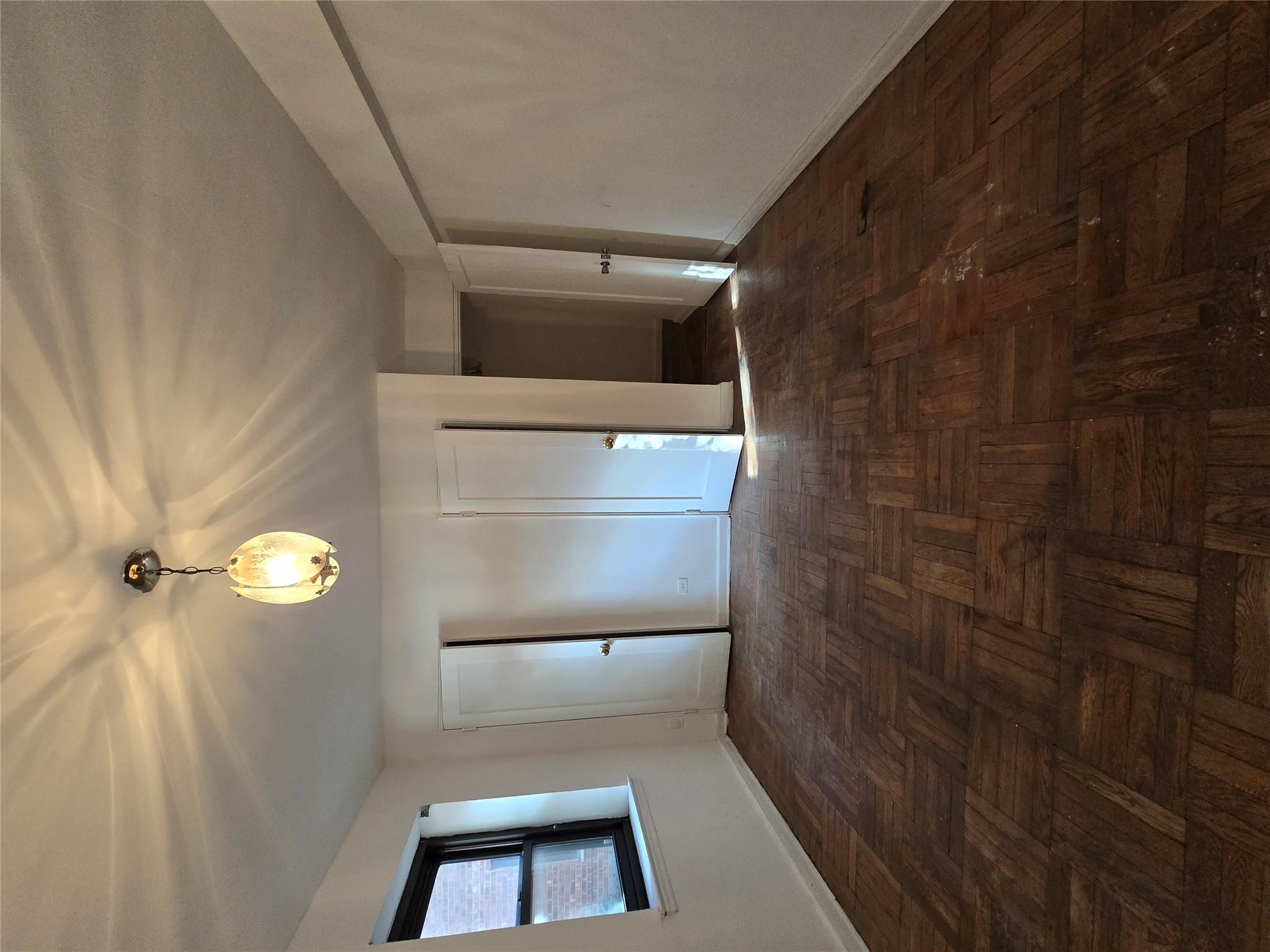 102-25 67th Road, Unit 1F Queens, NY 11375 - Photo 2 of 6 Spare room with dark parquet flooring