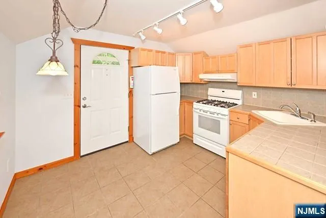 a kitchen with a refrigerator a stove top oven and cabinets