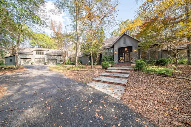 a front view of a house with a yard and many trees