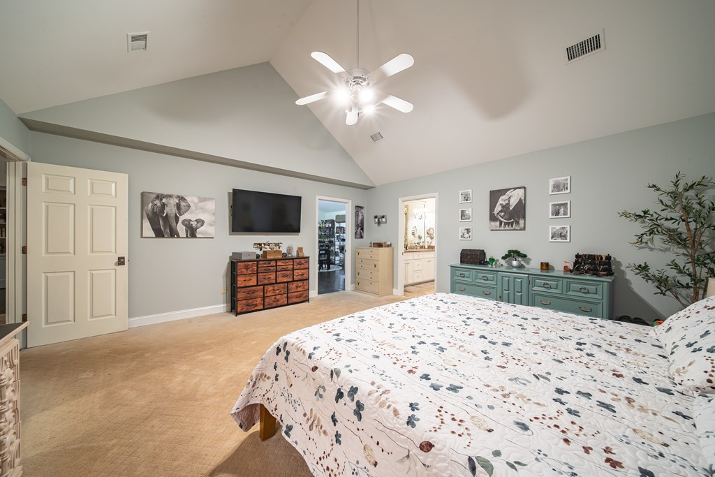 517 Double Churches Road Columbus, GA 31904 - Photo 32 of 96 a bedroom with a large bed a chandelier and a flat screen tv