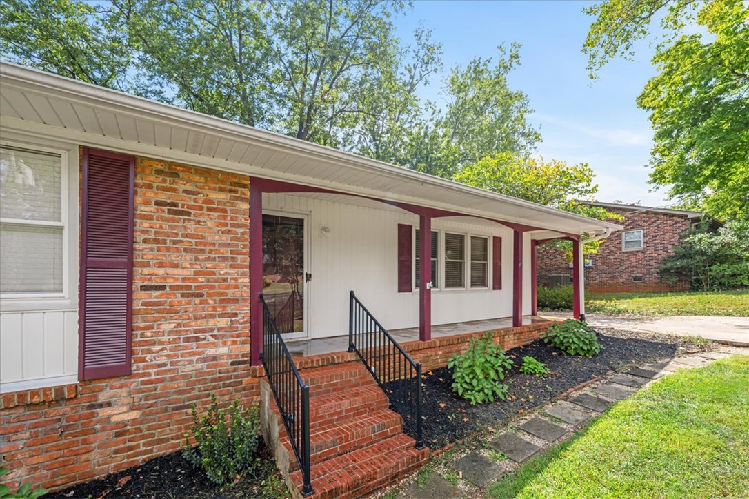 16 State Rd S-23-429 Greenville, SC 29609 - Photo 4 of 34 Brick steps and classic columns line a welcoming front porch set against mature trees.