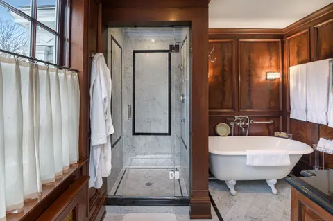 a bathroom with a tub a sink and a large mirror
