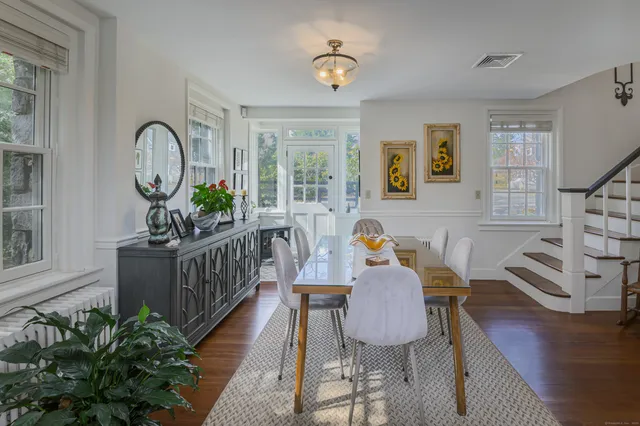 a dining room with furniture a potted plant and wooden floor