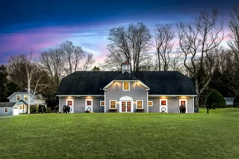 a view of a big house with a big yard and large trees