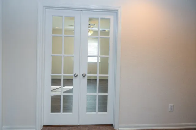 an empty room with wooden floor fan and windows