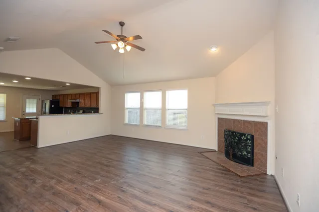 a view of a livingroom with a fireplace wooden floor and a ceiling fan