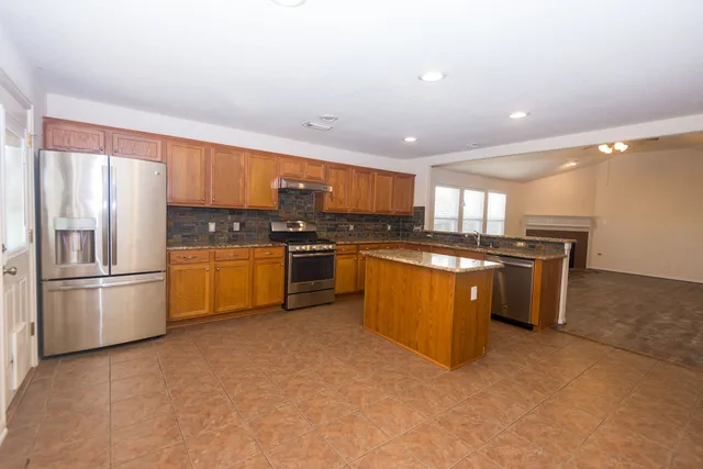 a kitchen with stainless steel appliances granite countertop a stove top oven a refrigerator a sink and a microwave
