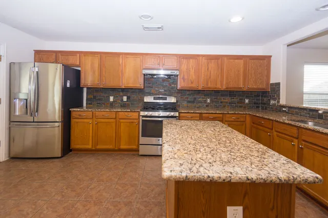 a kitchen with stainless steel appliances granite countertop a refrigerator sink and stove