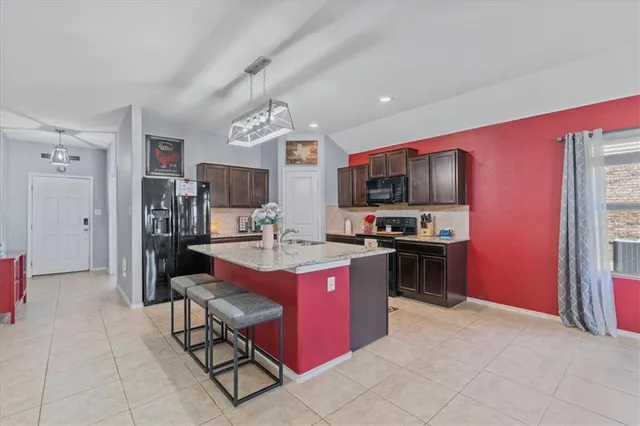 a kitchen with stainless steel appliances kitchen island granite countertop a stove refrigerator and microwave