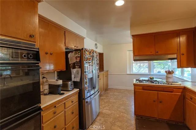 a kitchen with stainless steel appliances a sink cabinets and a window