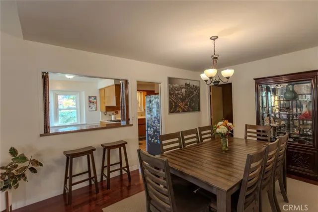 a dining room with wooden floor a chandelier a wooden table and chairs