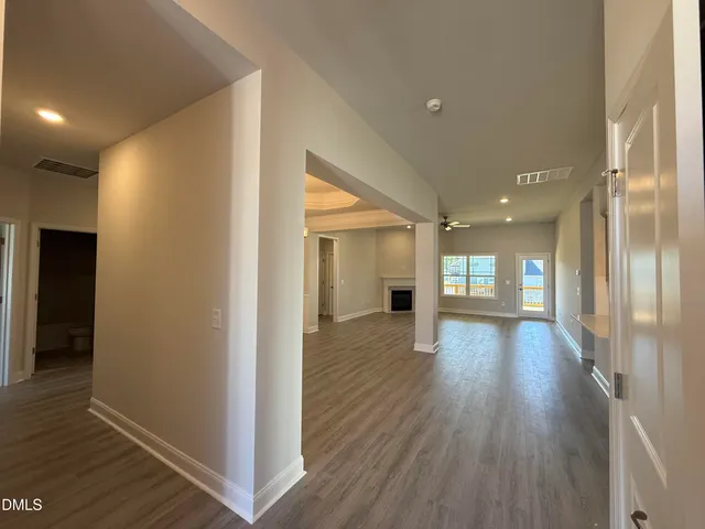 a view of an empty room with wooden floor and a bathroom