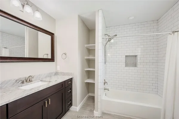 a bathroom with a granite countertop sink mirror bathtub and shower
