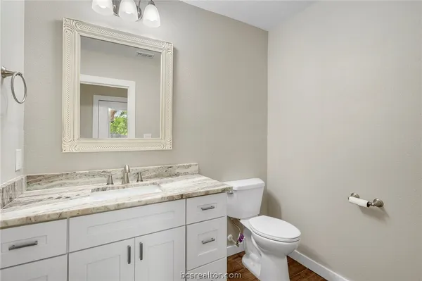 a bathroom with a granite countertop toilet sink and mirror