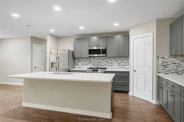 a kitchen with kitchen island a counter top space a stove and cabinets