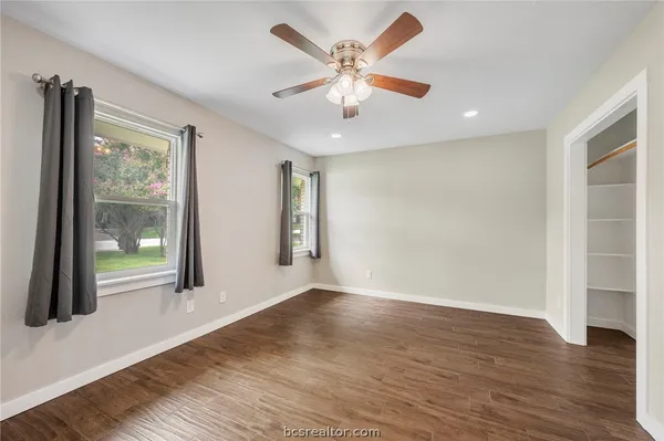 an empty room with wooden floor and windows