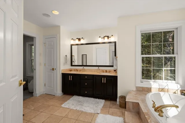 a spacious bathroom with a tub sink and mirror