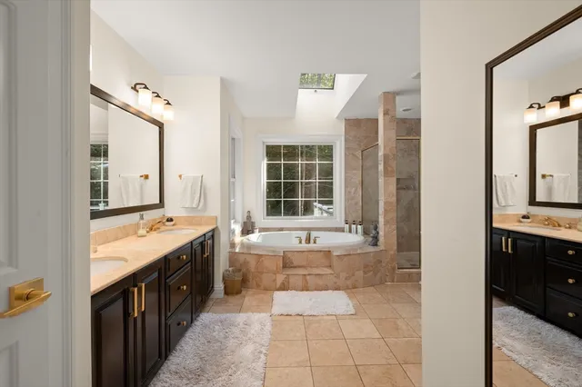 a spacious bathroom with a tub sink and mirror