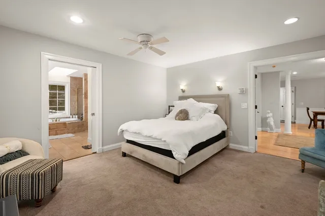 a bedroom with a bed a large window with table and chair