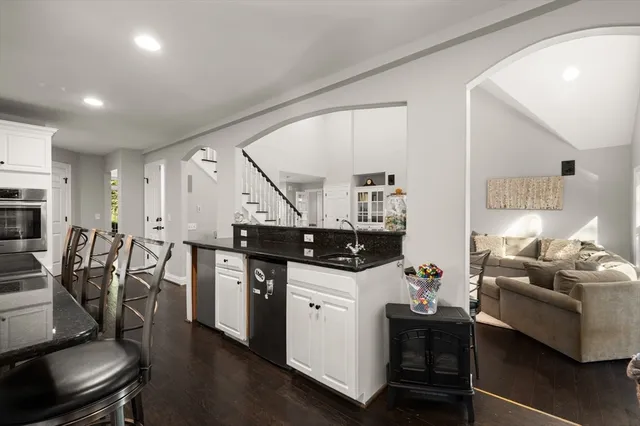 a kitchen with stainless steel appliances kitchen island a table chairs stove and white cabinets