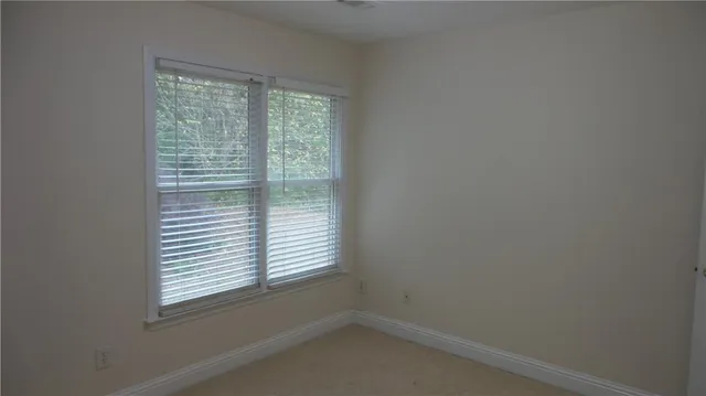 a view of an empty room with a chandelier fan and windows