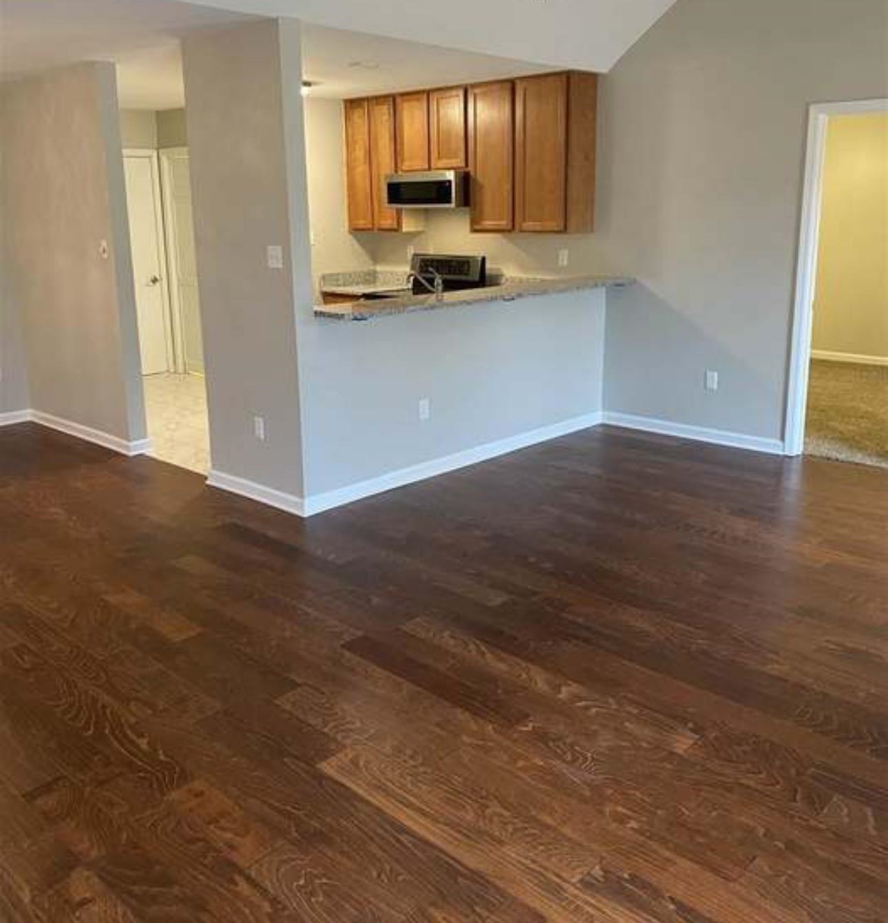 7001 Rockingham Road Memphis, TN 38125 - Photo 3 of 9 a kitchen with granite countertop wooden cabinets a stove a microwave and a window