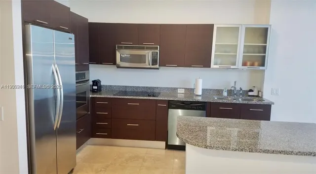 a kitchen with granite countertop a refrigerator and a stove top oven
