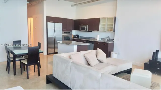 a kitchen with stainless steel appliances granite countertop a refrigerator a stove a sink a dining table and chairs