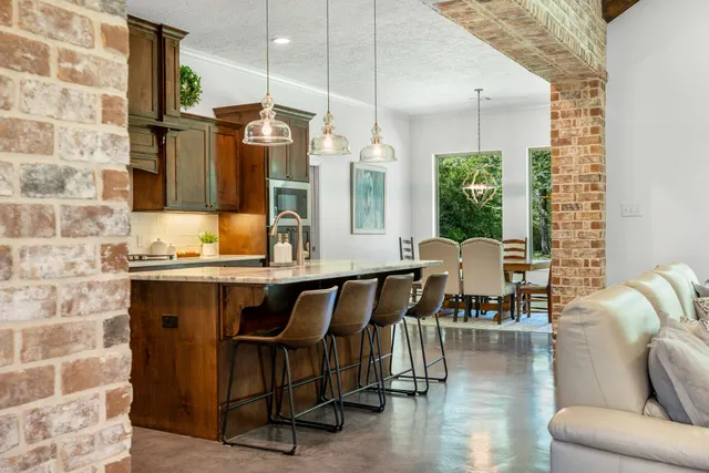 a living room with couches chairs and kitchen view with wooden floor