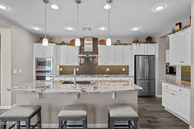 a kitchen with stainless steel appliances granite countertop a table chairs and a refrigerator