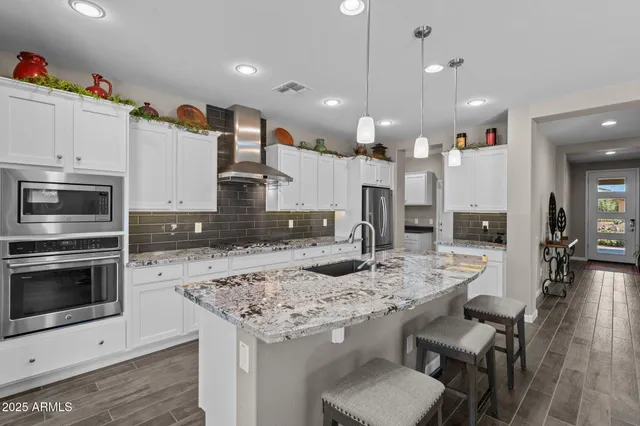 a kitchen with stainless steel appliances kitchen island granite countertop a stove a sink a oven a dining table and chairs