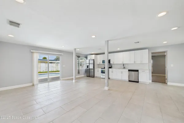 an empty room with kitchen and windows