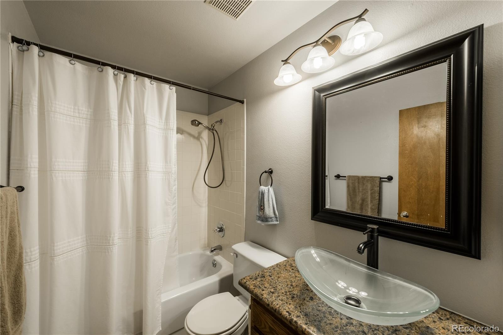 8583 Redstone Street Highlands Ranch, CO 80126 - Photo 18 of 25 a bathroom with a granite countertop sink toilet and shower