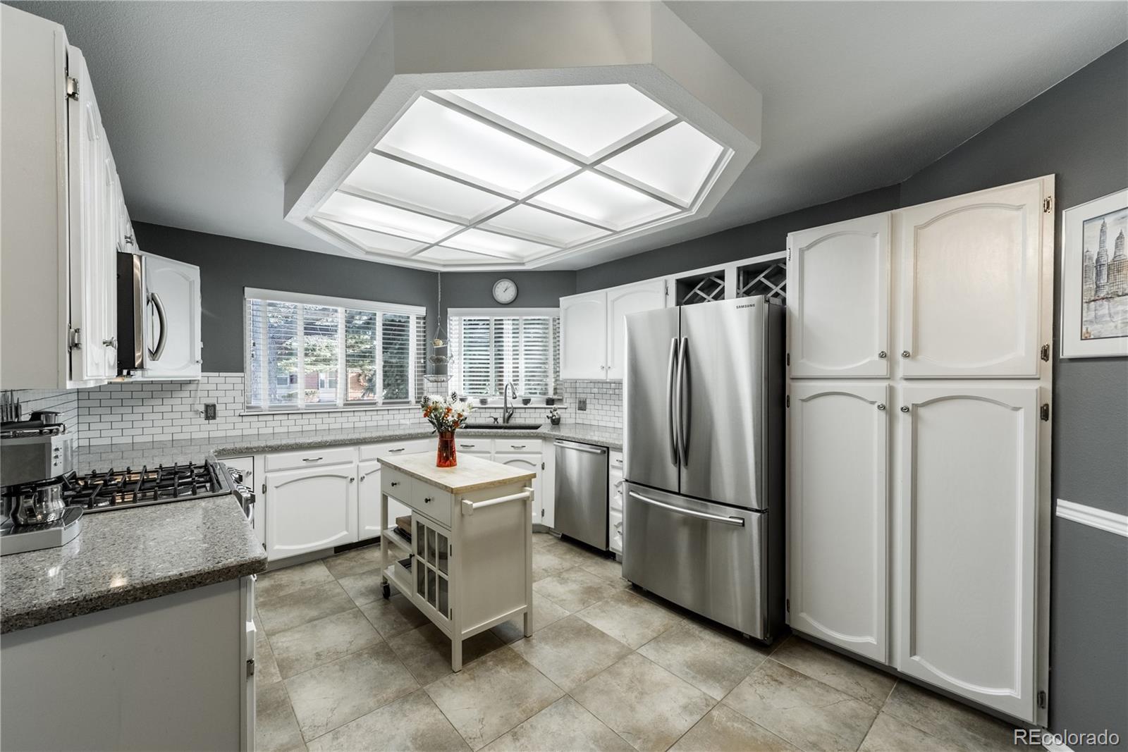8583 Redstone Street Highlands Ranch, CO 80126 - Photo 3 of 25 a kitchen with granite countertop stainless steel appliances a sink and a refrigerator