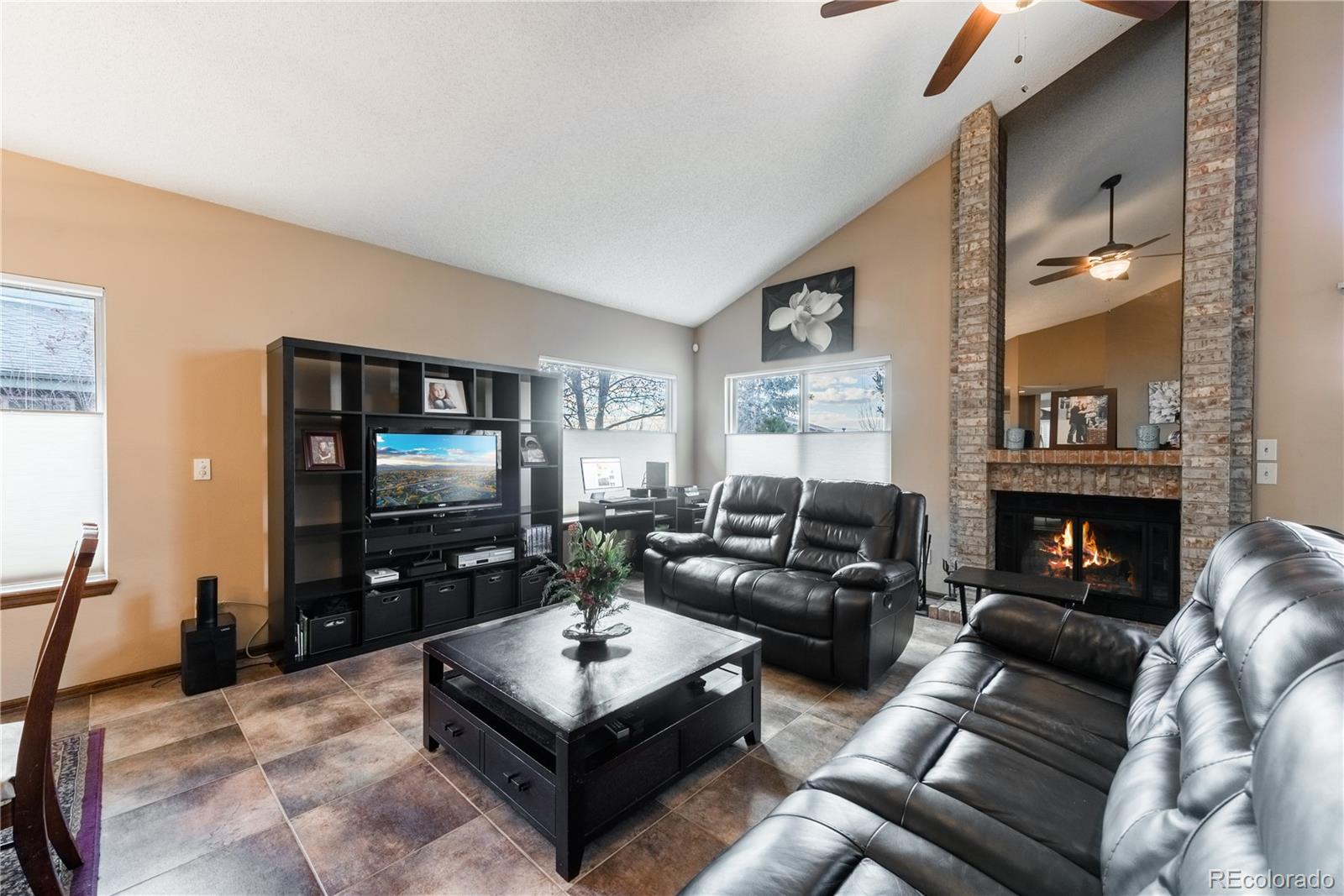 8583 Redstone Street Highlands Ranch, CO 80126 - Photo 9 of 25 a living room with furniture a flat screen tv and a fireplace