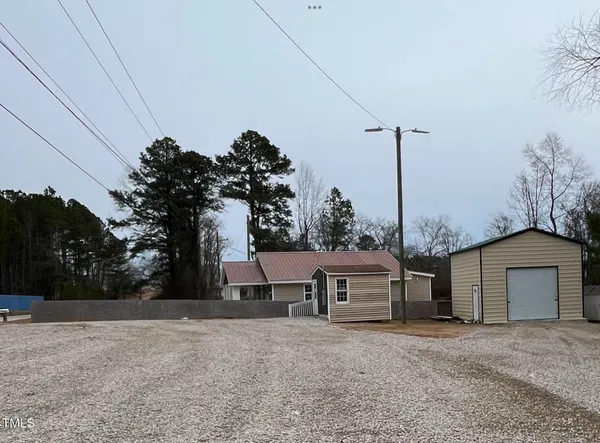 a front view of a house with a garden and trees