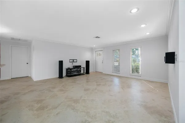 a view of an empty room with a window and a kitchen