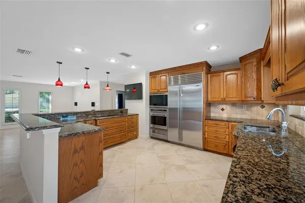 a kitchen with stainless steel appliances granite countertop a refrigerator a stove and wooden cabinets