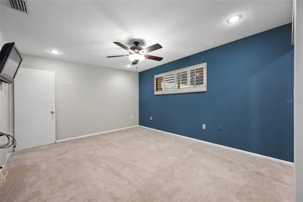 an empty room with a fan & a window