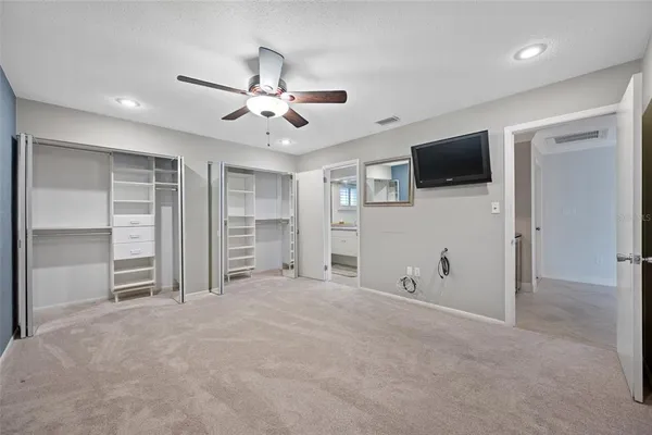 a view of an empty room with a ceiling fan window and kitchen view