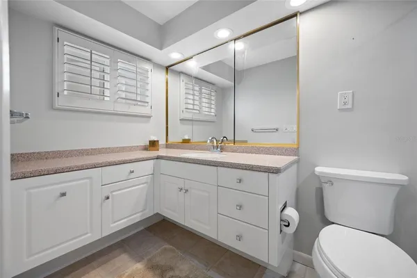 a bathroom with a toilet a sink a mirror a and a window
