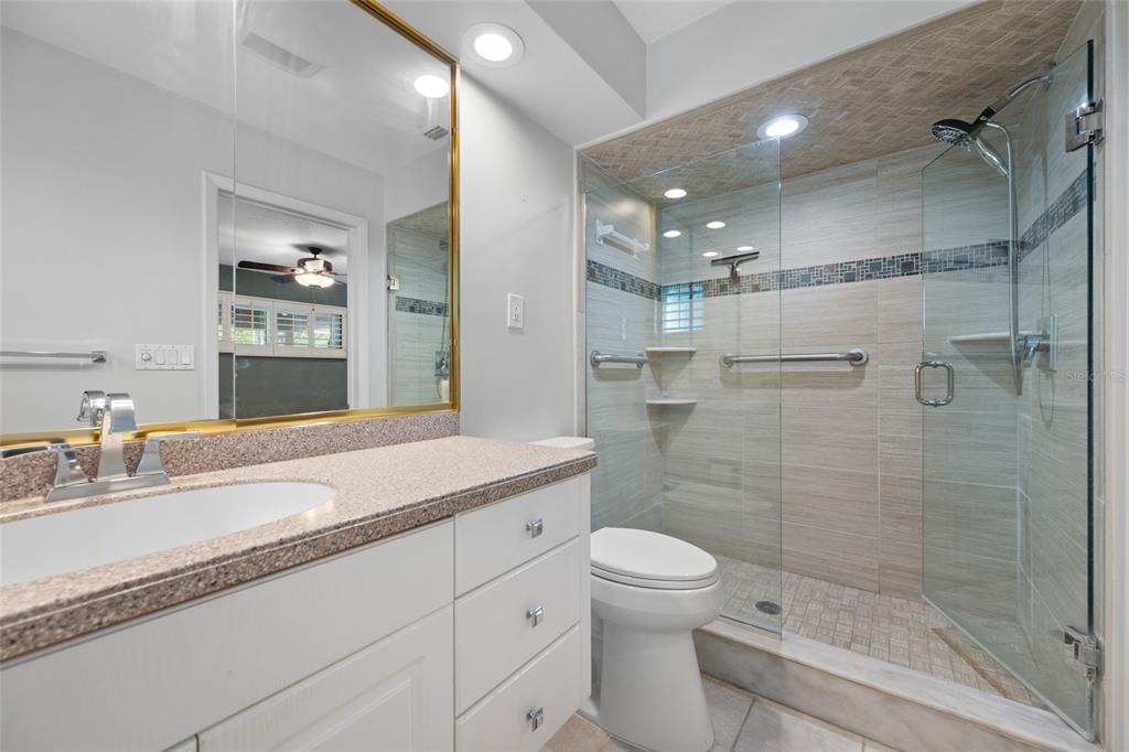 5473 97th Way North St. Petersburg, FL 33708 - Photo 33 of 62 a bathroom with a granite countertop sink a toilet a mirror and shower