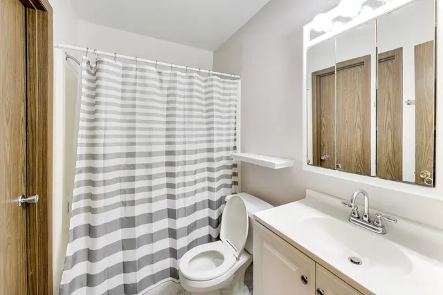 a bathroom with a sink a toilet a mirror and shower curtain