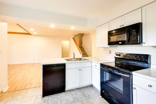 a kitchen with a sink and a stove top oven with wooden floor