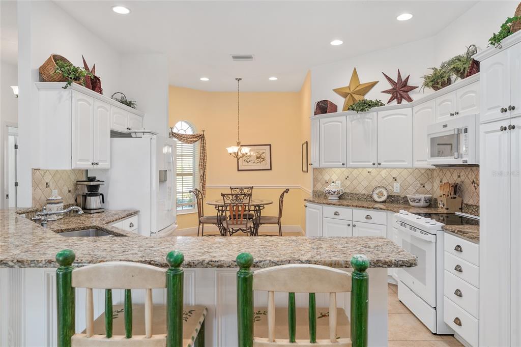 2053 Beecher Path The Villages, FL 32162 - Photo 20 of 44 a kitchen with stainless steel appliances kitchen island granite countertop a stove a sink and a refrigerator
