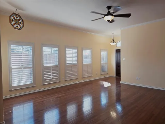 a view of an empty room with a window and wooden floor